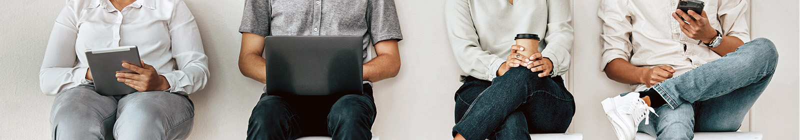 People sitting in chairs holding a tablet, laptop, a cup of coffee and a mobile phone