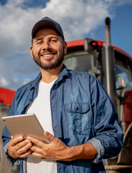 a farmer standing in front of a tractor holding a tablet