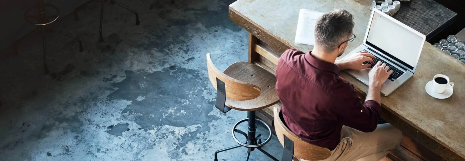 a man working on his laptop at a coffee shop table